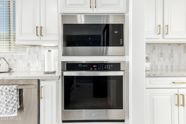 kitchen featuring backsplash, appliances with stainless steel finishes, light stone counters, and white cabinets