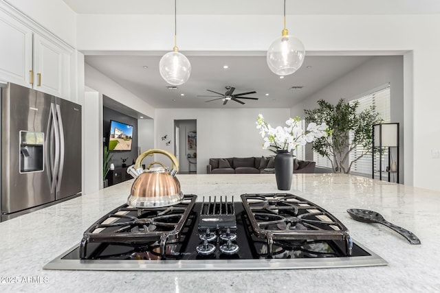 kitchen with white cabinets, decorative light fixtures, stainless steel fridge with ice dispenser, and black cooktop