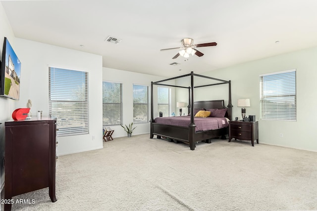 bedroom featuring ceiling fan, light carpet, and multiple windows