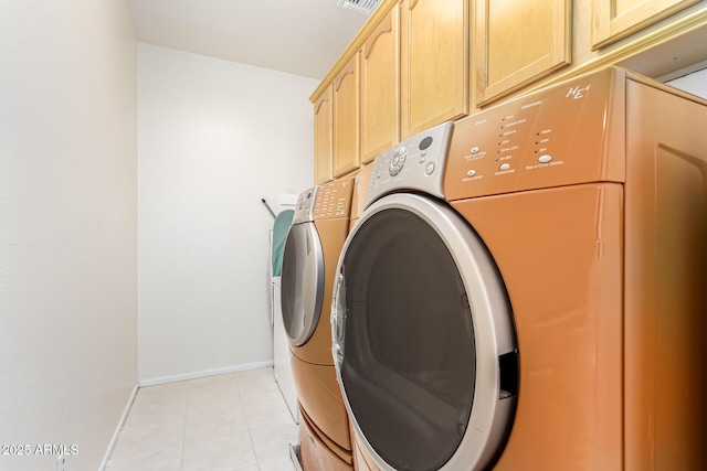 laundry area featuring separate washer and dryer, light tile patterned floors, and cabinets