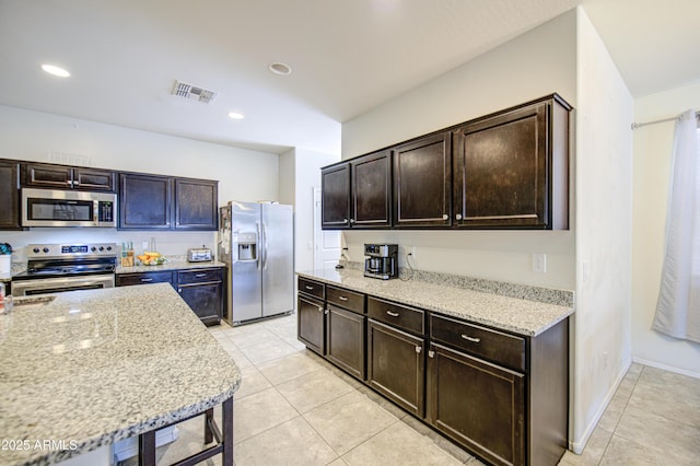 10856 E Primrose Ct, Florence, AZ 85132 - kitchen featuring light tile patterned floors, light stone countertops, dark brown cabinets, visible vents, and stainless steel appliances