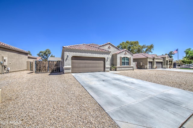 10856 E Primrose Ct, Florence, AZ 85132 - mediterranean / spanish-style home featuring concrete driveway, stucco siding, an attached garage, a tiled roof, and a gate