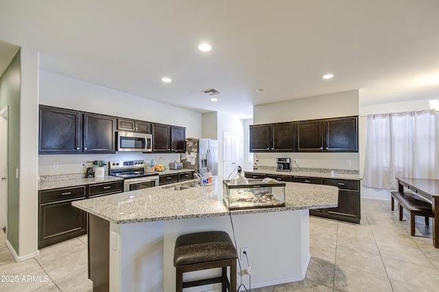 10856 E Primrose Ct, Florence, AZ 85132 - kitchen with an island with sink, light stone countertops, visible vents, appliances with stainless steel finishes, and a sink