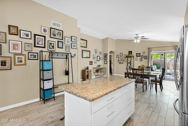15391 W Yucatan Dr, Surprise, AZ 85379 - kitchen featuring arched walkways, a ceiling fan, freestanding refrigerator, white cabinets, and light wood-style flooring