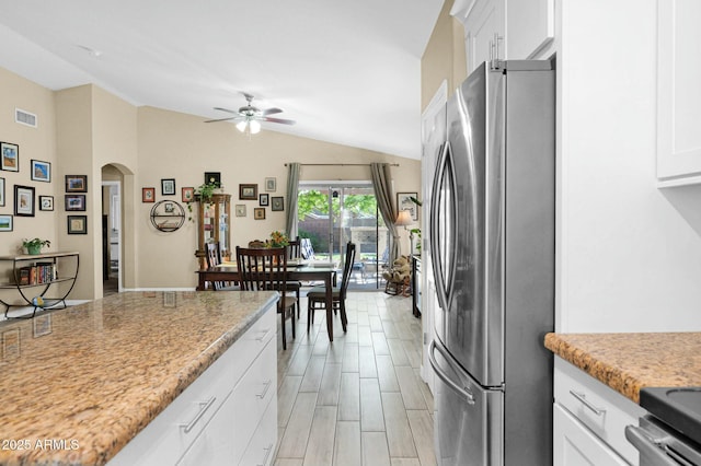 15391 W Yucatan Dr, Surprise, AZ 85379 - kitchen featuring freestanding refrigerator, arched walkways, lofted ceiling, ceiling fan, and white cabinets