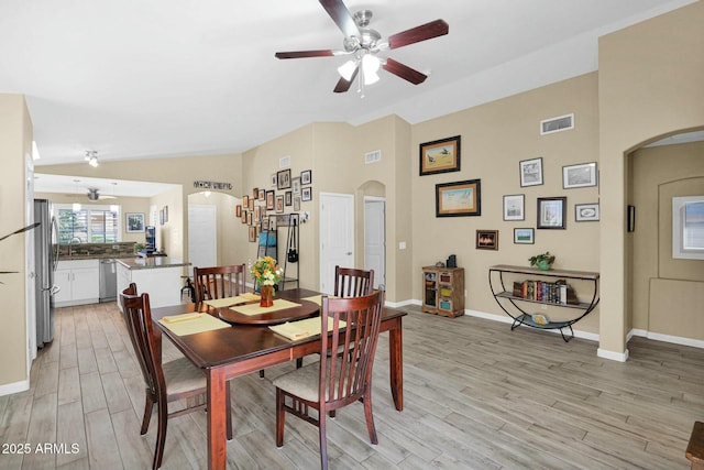 15391 W Yucatan Dr, Surprise, AZ 85379 - dining room featuring arched walkways, a ceiling fan, light wood finished floors, baseboards, and lofted ceiling