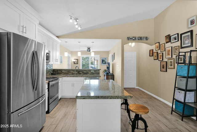 15391 W Yucatan Dr, Surprise, AZ 85379 - kitchen featuring appliances with stainless steel finishes, a sink, a breakfast bar, light wood finished floors, and vaulted ceiling