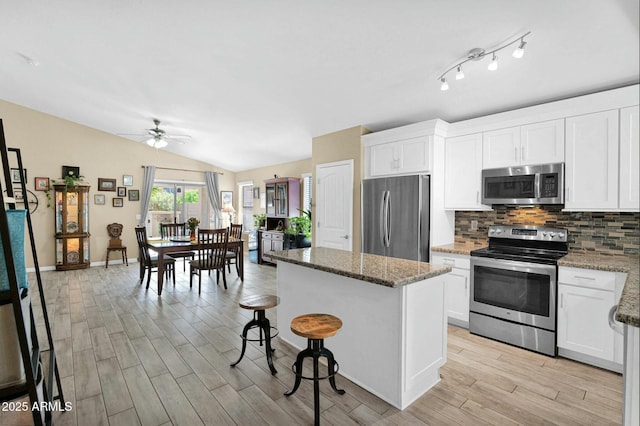 15391 W Yucatan Dr, Surprise, AZ 85379 - kitchen with appliances with stainless steel finishes, a kitchen island, a ceiling fan, decorative backsplash, and light wood-type flooring