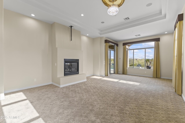 unfurnished living room with a tray ceiling and light colored carpet