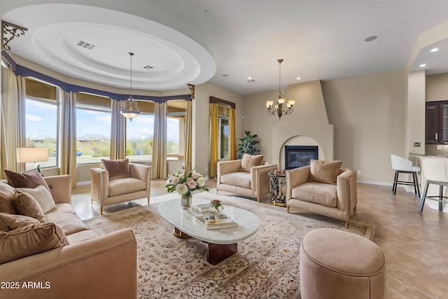 tiled living room featuring a notable chandelier, a large fireplace, and a raised ceiling