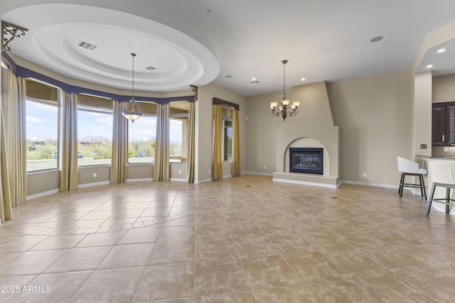 unfurnished living room featuring a tray ceiling, a fireplace, light tile patterned floors, and a chandelier