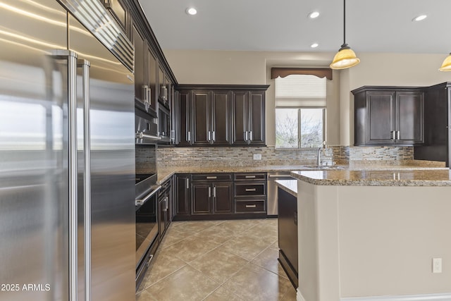 kitchen featuring backsplash, light stone counters, stainless steel appliances, and decorative light fixtures