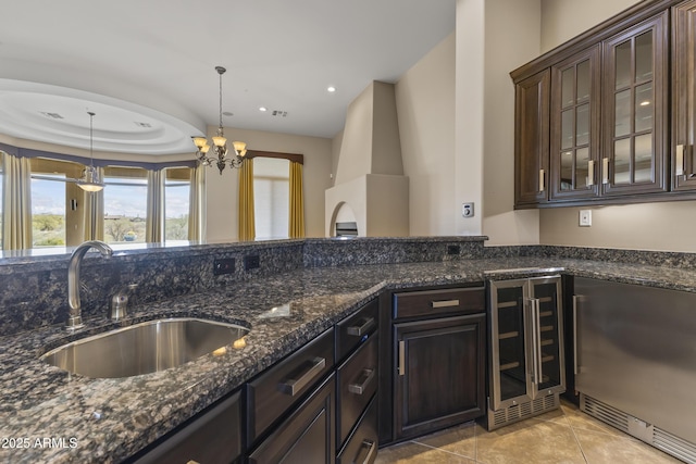 kitchen featuring dark brown cabinetry, sink, wine cooler, dark stone counters, and pendant lighting