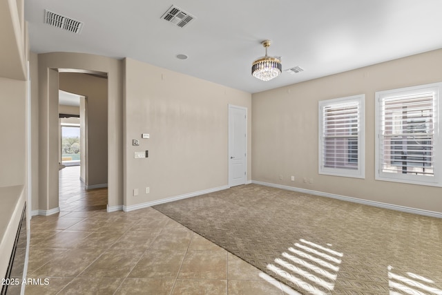 spare room with a chandelier and light tile patterned flooring