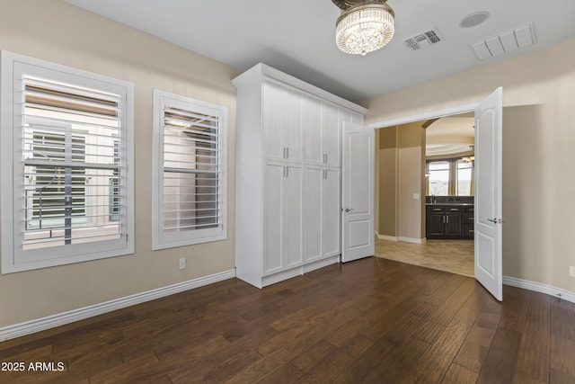 unfurnished bedroom with dark hardwood / wood-style flooring and a notable chandelier