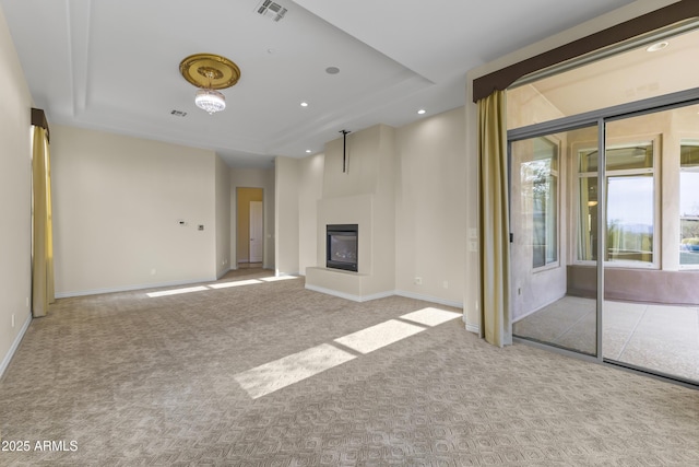 unfurnished living room featuring light carpet and a tray ceiling