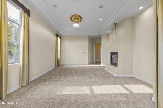 unfurnished living room with a tray ceiling and light colored carpet