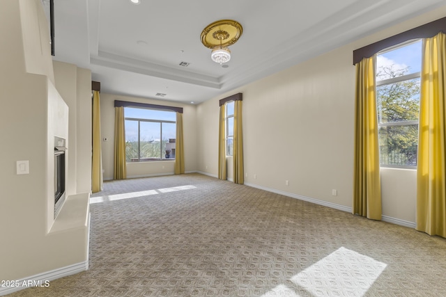 carpeted spare room with a raised ceiling