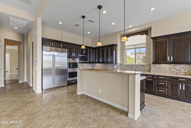 kitchen featuring dark brown cabinetry, tasteful backsplash, light stone counters, built in appliances, and pendant lighting