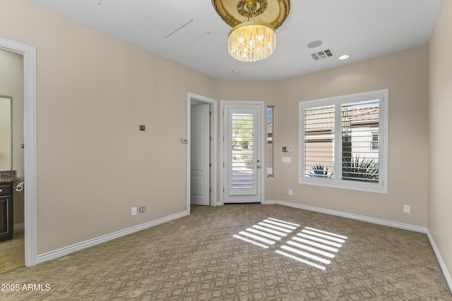 unfurnished room featuring light carpet and an inviting chandelier