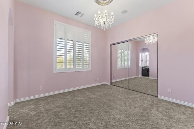 unfurnished bedroom with a notable chandelier, carpet floors, and a closet