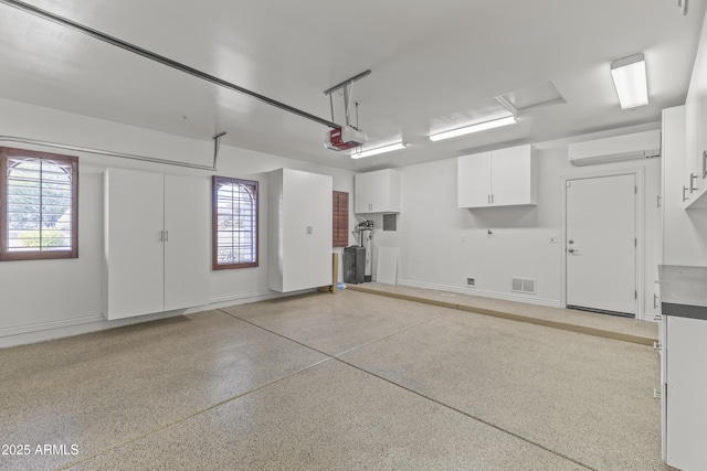 garage featuring a wall mounted air conditioner and a garage door opener