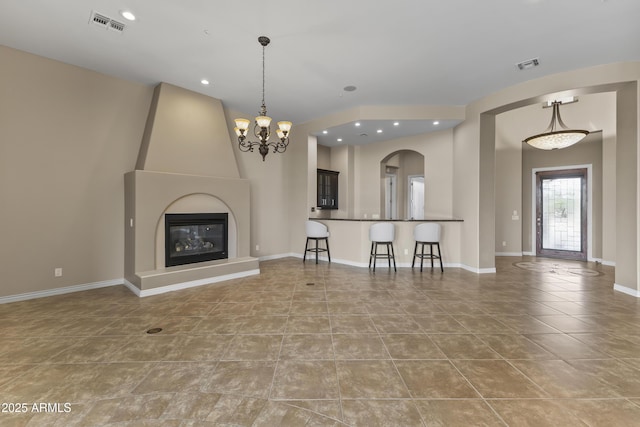 unfurnished living room featuring light tile patterned floors, a large fireplace, and an inviting chandelier