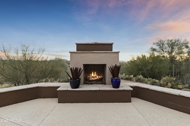 patio terrace at dusk featuring exterior fireplace