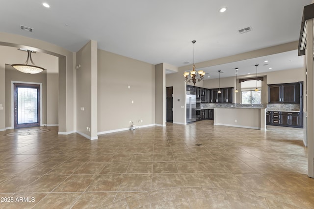 unfurnished living room featuring plenty of natural light, light tile patterned floors, and an inviting chandelier