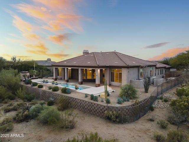 back house at dusk featuring a patio area