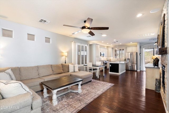 living area featuring ceiling fan, visible vents, dark wood-style floors, and recessed lighting