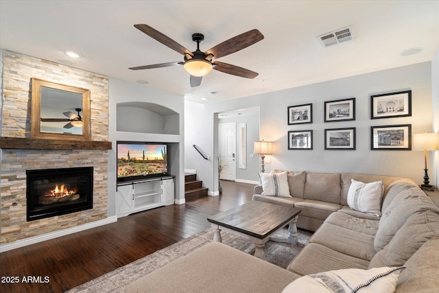 living room featuring visible vents, built in features, wood finished floors, a fireplace, and baseboards