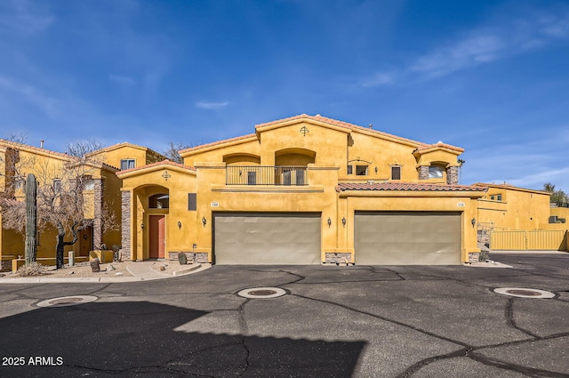 mediterranean / spanish-style house with stone siding, a tiled roof, a balcony, and stucco siding