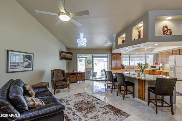 living room featuring light tile patterned floors, vaulted ceiling, and ceiling fan