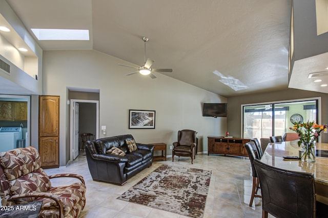 living room with independent washer and dryer, a skylight, high vaulted ceiling, light tile patterned floors, and ceiling fan