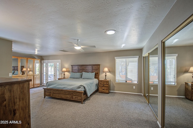 bedroom with ceiling fan, two closets, light colored carpet, and a textured ceiling