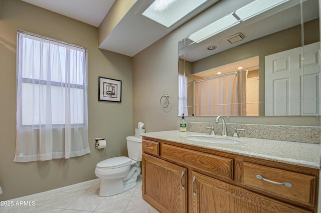 bathroom featuring a skylight, vanity, tile patterned floors, toilet, and walk in shower