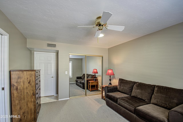 carpeted living room with ceiling fan and a textured ceiling