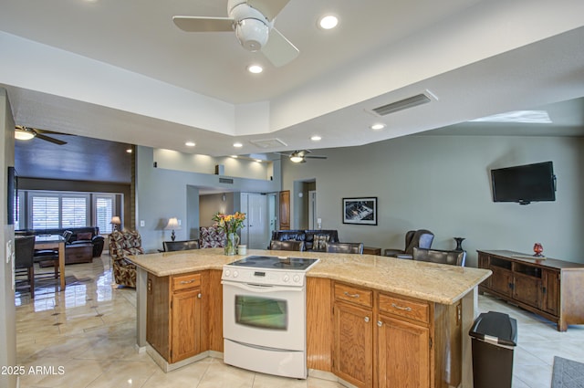 kitchen with white range with electric stovetop, a breakfast bar area, a center island, light tile patterned floors, and ceiling fan