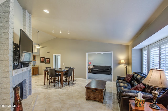 tiled living room featuring lofted ceiling, a large fireplace, and ceiling fan