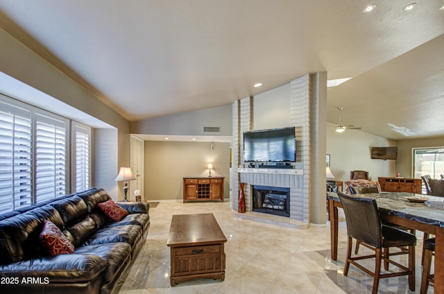 living room featuring lofted ceiling, light tile patterned floors, ceiling fan, and a brick fireplace