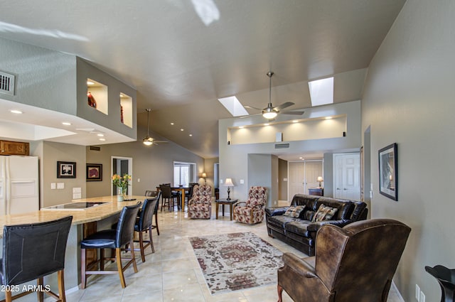 tiled living room with vaulted ceiling with skylight and ceiling fan