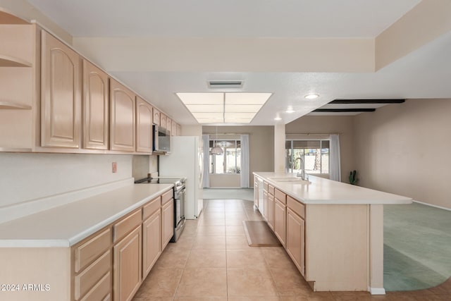 kitchen featuring light tile patterned flooring, appliances with stainless steel finishes, light brown cabinetry, sink, and an island with sink