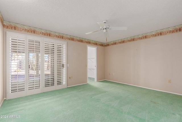 spare room featuring ceiling fan, a textured ceiling, and carpet