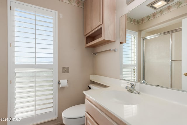 bathroom with a wealth of natural light, vanity, toilet, and an enclosed shower