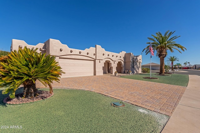 pueblo revival-style home featuring a front lawn and a garage