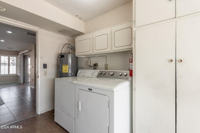 washroom featuring a textured ceiling, dark tile patterned flooring, cabinets, washing machine and dryer, and electric water heater