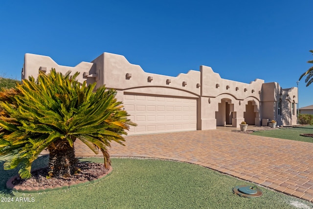 adobe home featuring a garage and a front yard