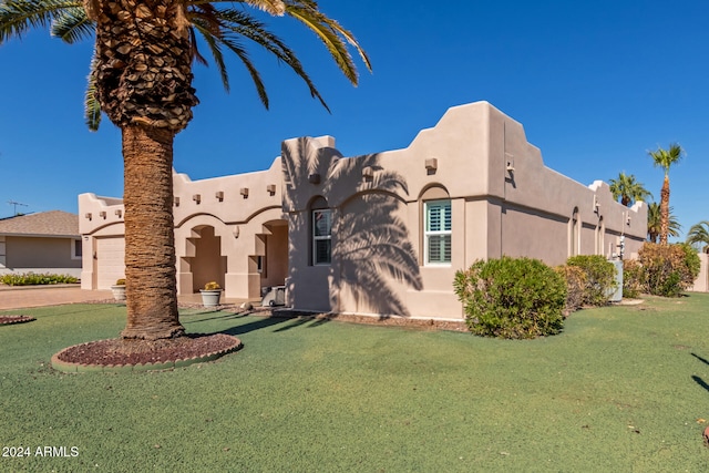 pueblo-style house with a garage and a front yard