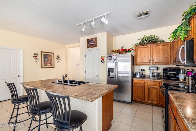 kitchen featuring appliances with stainless steel finishes, sink, a breakfast bar, and a kitchen island with sink